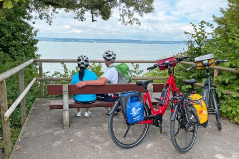 Cyclists on a bench with a view of Lake Constance