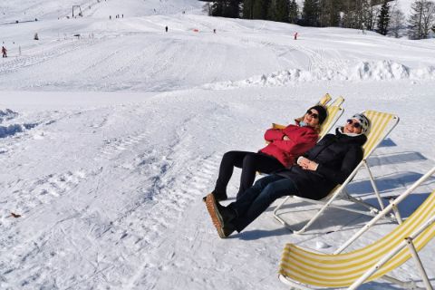 Zwei Skifahrer sitzen im Liegestuhl und genießen die Sonne
