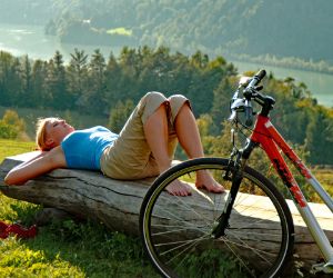 Cyclist enjoy the sun lying on a tree
