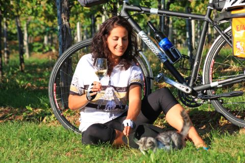 Radfahrerin sitzt mit Weinglas vor ihrem Rad