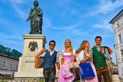 Vier Personen in Tracht vor der Mozart Statue