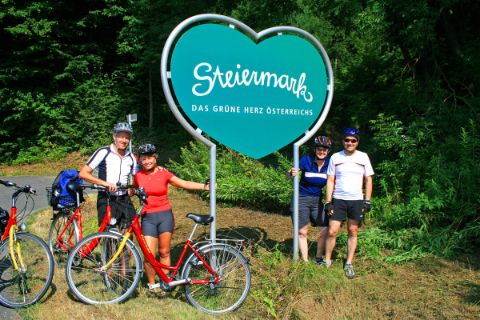 Cyclists in front of the logo of Styria