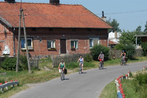 Cyclists in front of a typical Masurian house