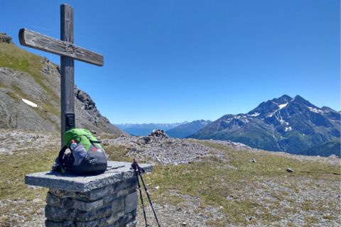 Gipfelkreuz mit Panoramablick und grünem Rucksack