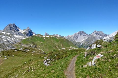 Hiking trail over the Alps with distant view of peaks