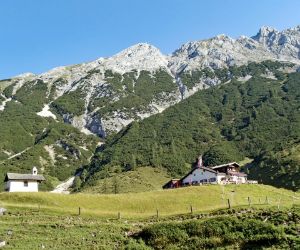 Blick beim Wandern am Tirolerweg auf die Berge und Hütte
