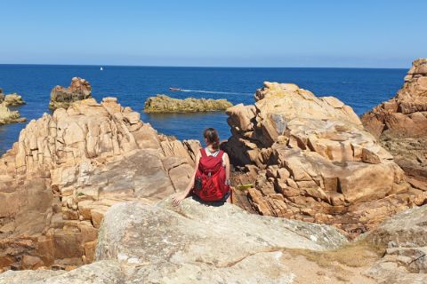 Wanderer genießt den tollen Ausblick auf die roten Granitfelsen und das Meer