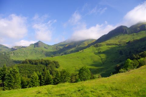 Wiesenfelder und Bergkulisse beim Wandern am Puy Saint
