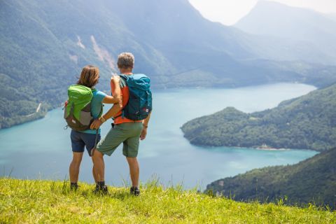 Hikers admire the beautiful Lake Molveno surrounded by mountains 