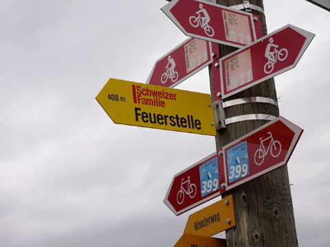 Wegweiser der viele Rad und Fusswege anzeigt, aber auch den Weg zur Feuerstelle der Zeitschrift Schweizer Familie.