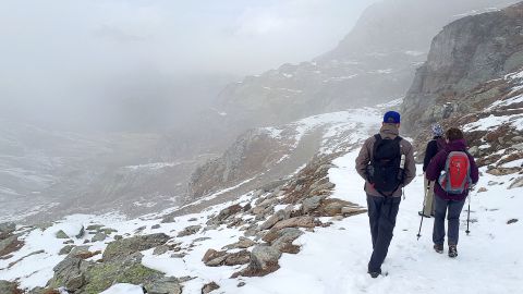 Srei Wanderer laufen uf dem Schnee auf bewölkten Bergen.