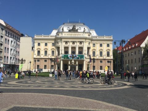 Grosser Platz mit Mosaikmuster vor einem prachtvollen Gebäude.