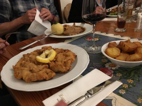 Ein Tisch mit panierem Schnitzel, Bratkartoffeln und Braten mit Knödel. Das muss ein Deutsches Restaurant sein.