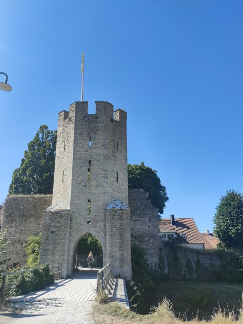 Eine Velofahrerin fährt durch den Turm einer Mittelalter Burg in Gotland. 
