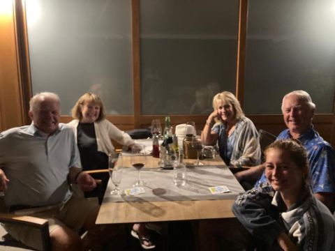 5 Personen sitzen im halbdunkeln an einem Tisch in Porec und essen zu Abend. 