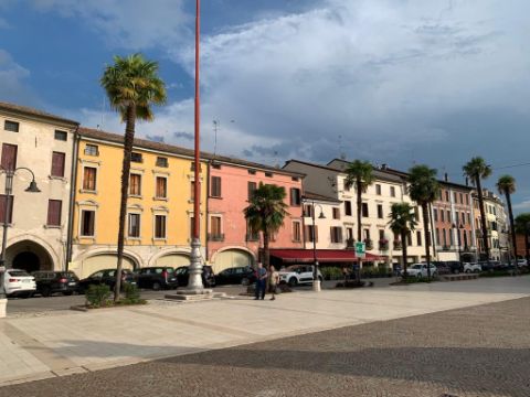 Die Fasse in Portogruaro ist mit bunten Häusern versehen, Palmen stehen davor. 