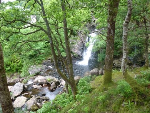 Ein Wasserfall stürzt in einem Wald in die Tiefe am West-Highland-Way in Schottland.