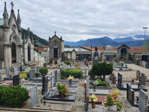 Ein Friedhof mit vielen Gräbern und eine traditionelle Trauerhalle in der Nähe von Lugano.