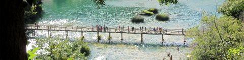 Eine schmale Fussgängerbrücke in Dalmatien führt über das Wasser.