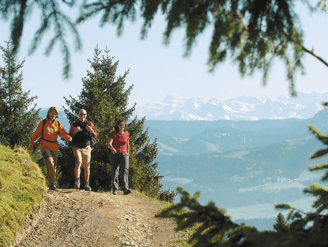 Eine Gruppe Wanderer auf den steinigen Wanderwegen mit Blick auf die verschneite Bergkette