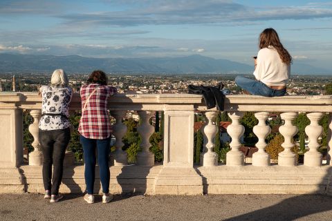 Drei Frauen machen auf einer Brücke Pause. Zwei lehnen sich am Geländer an und eine Frau sitzt darauf. Alle schauen sich die schöne Aussicht an.