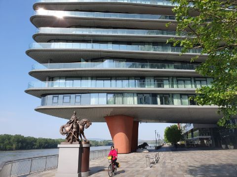 Eine Velofahrerin fährt unter einem modernen Gebäude in Bratislava an der Donau durch.