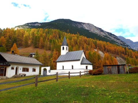Eine kleine Kirche mit einem Haus daneben, am Fusse des Berges.
