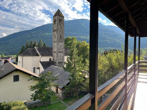 Von einem Balkon sieht man auf eine Steinkirche in Olivone. 