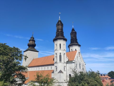 Eine weisse Kirche mit schwarzen Türmen steht im Zentrum von Visby auf Gotland. 