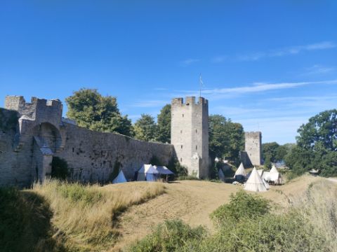 Vor einer Burgmauer stehen Tippi-Zelte für das Mittelalterfest. 