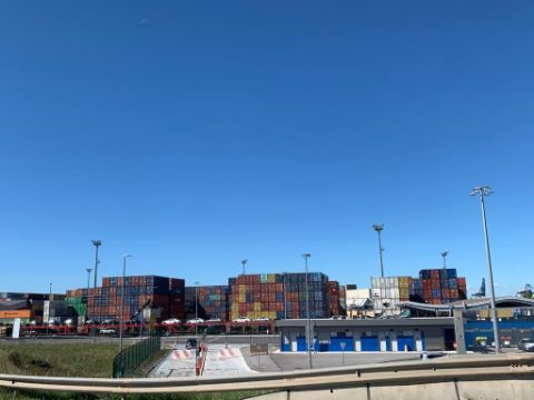 Man blickt auf ein grosses Schiff gefüllt mit Containern im Hafen. 