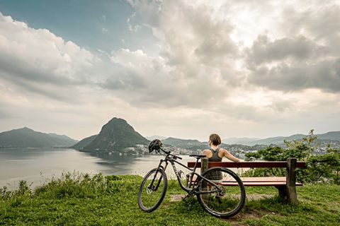 Velofahrerin geniesst die Sicht auf den Luganersee. Lugano Bike. Veloferien mit Eurotrek.