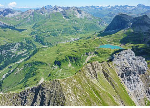 Blick auf Arlberg und die grüne Natur mit Bergsee aus der Vogelperspektive. 