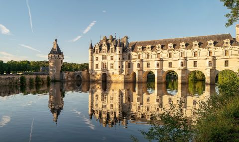 Über die Loire sieht man auf das Wasserschloss Chenonceau im Loiretal, dass sich im Wasser spiegelt.