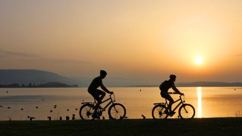 Cyclistes devant un lac au coucher du soleil