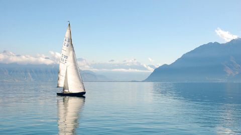 Ein Segelboot fährt an einem sonnigen Tag auf dem Genfersee.