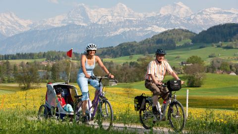 Deux cyclistes avec un e-bike Flyer et une remorque pour enfants, sur la route naturelle de la Herzroute.