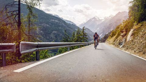 Radfahrer auf einer asphaltierten Strasse in den Bergen