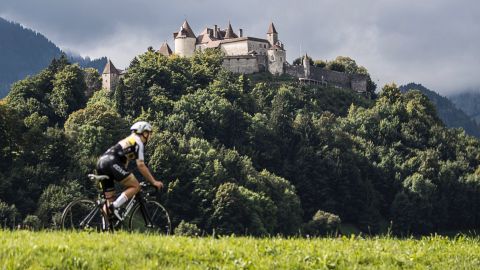 Cyclist in front of a densely wooded hill with a castle