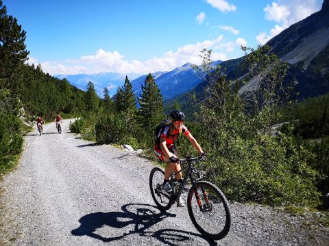 Three mountain bikers ride on a gravel track in the Swiss National Park.