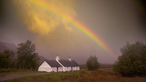 Un arc-en-ciel s'étire au-dessus d'une maison blanche lors d'une randonnée sur le West Highland Way en Écosse.